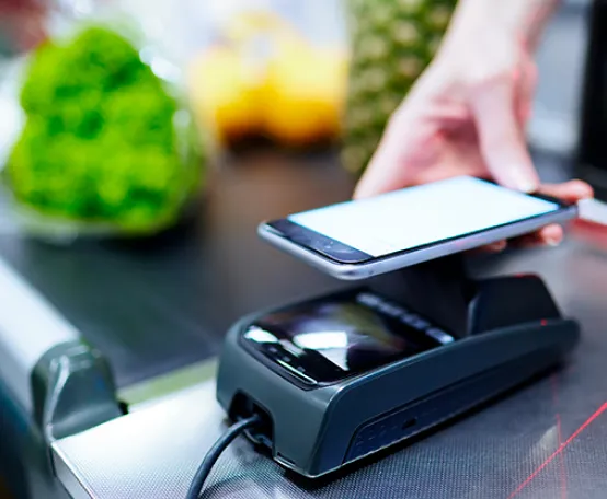 Pessoa encostando celular na maquininha para fazer pagamento