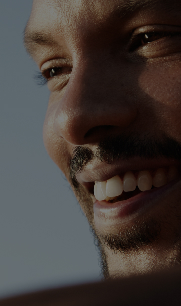 Mulher com fone e microfone em frente a computador e sorrindo