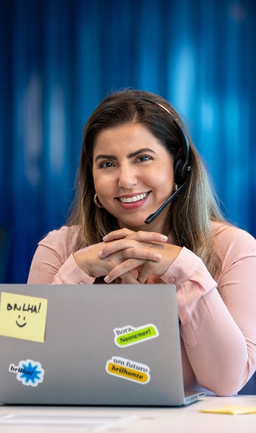 Mulher com fone e microfone em frente a computador e sorrindo