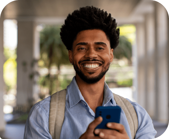 Homem segurando cartão de crédito Neon em frente a portão e sorrindo