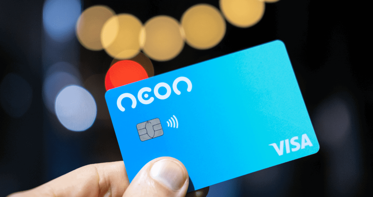 Mão segurando cartão Neon em frente a fundo desfocado
