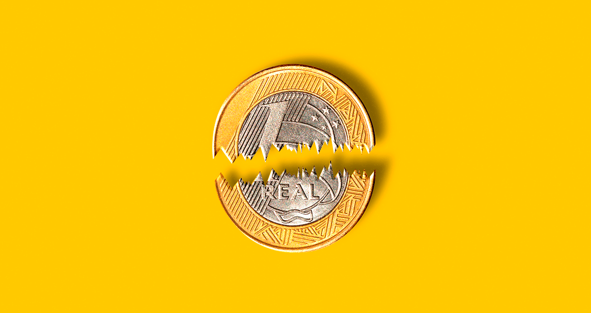 Moeda de um real partida ao meio sobre fundo amarelo