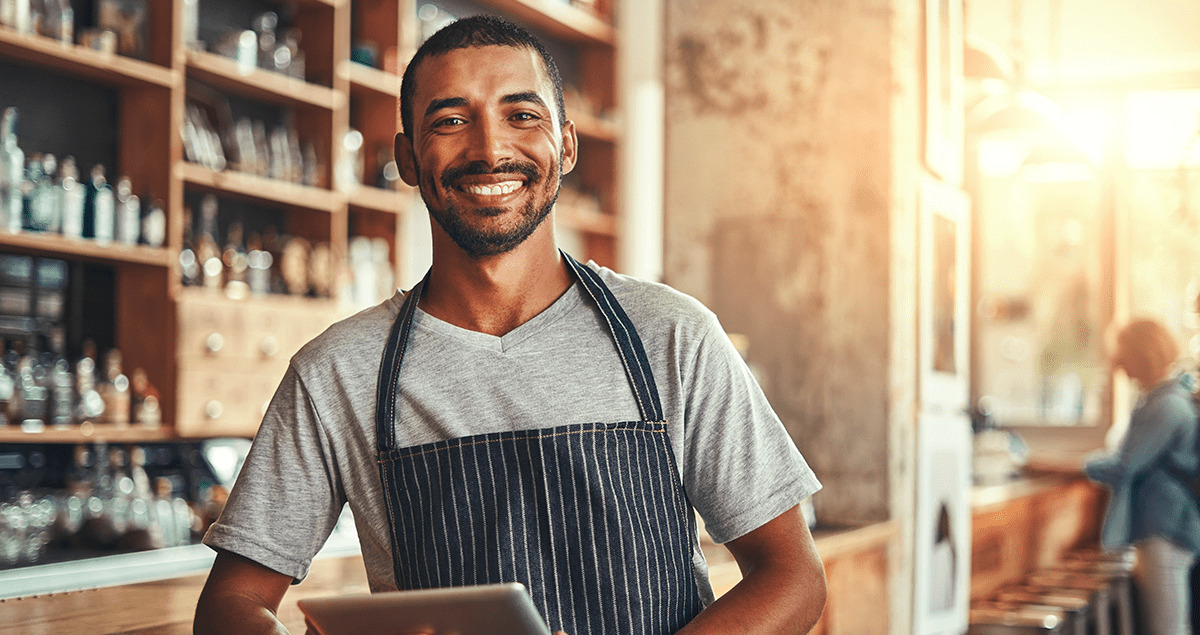 Homem com avental em loja sorrindo