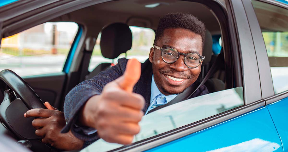 Homem fazendo positivo com as mãos dentro de carro