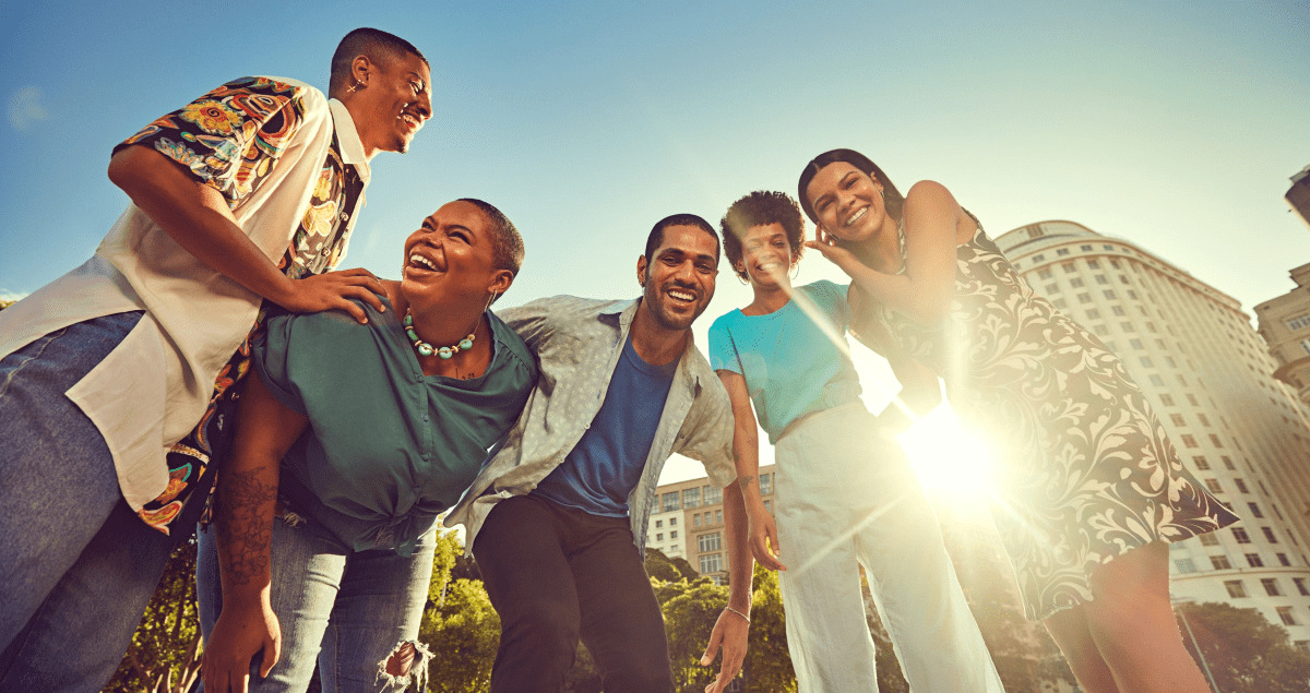 Grupo de pessoas sorrindo ao ar livre com sol ao fundo