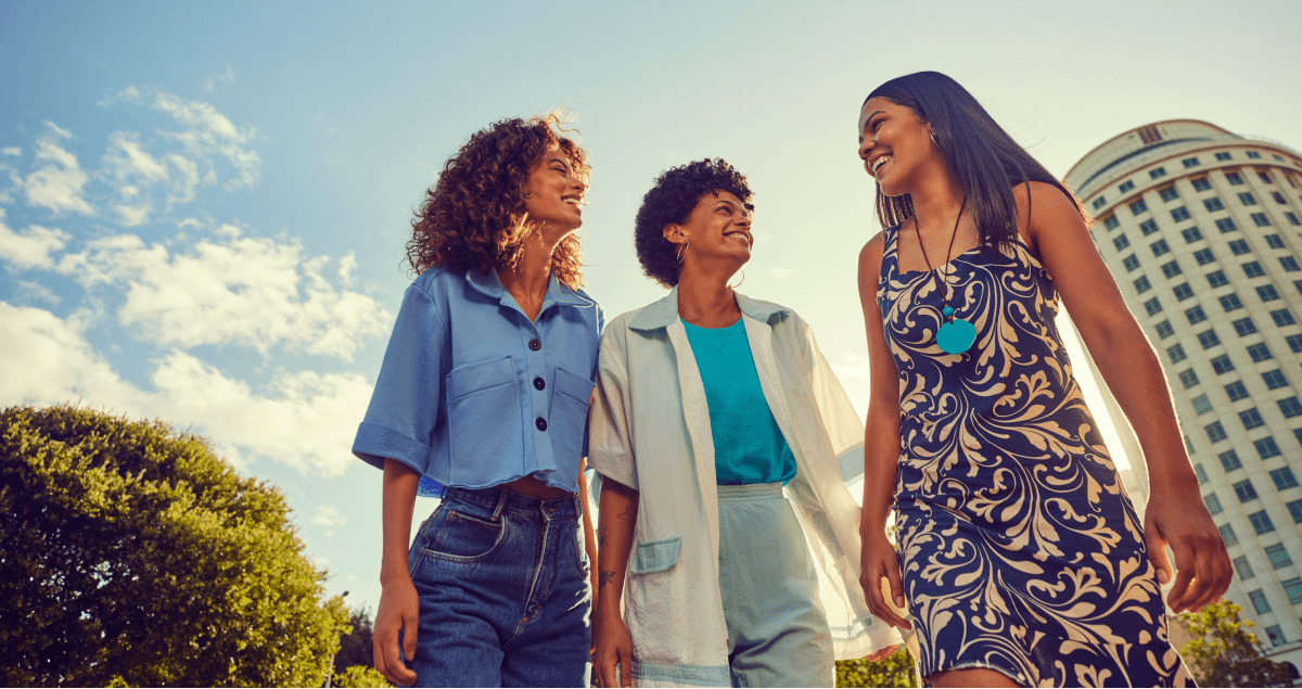 Três mulheres ao ar livre sorrindo