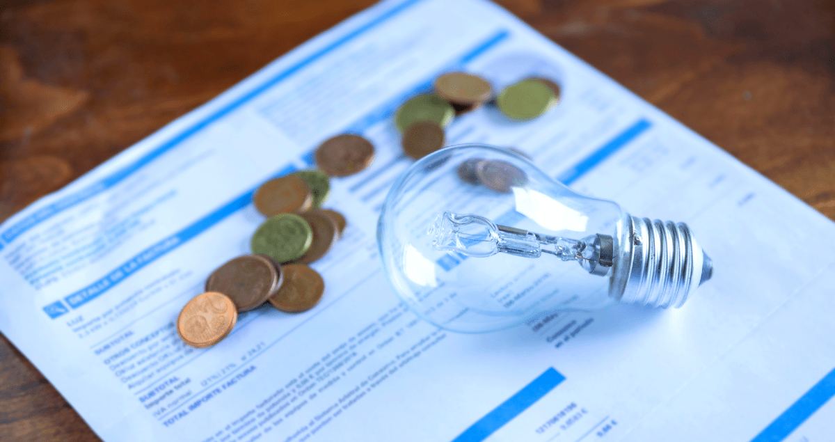 Lâmpada e moedas sobre conta de energia