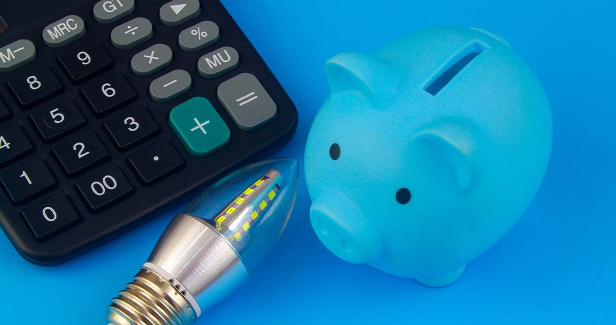 Porquinho ao lado de lâmpada e calculadora