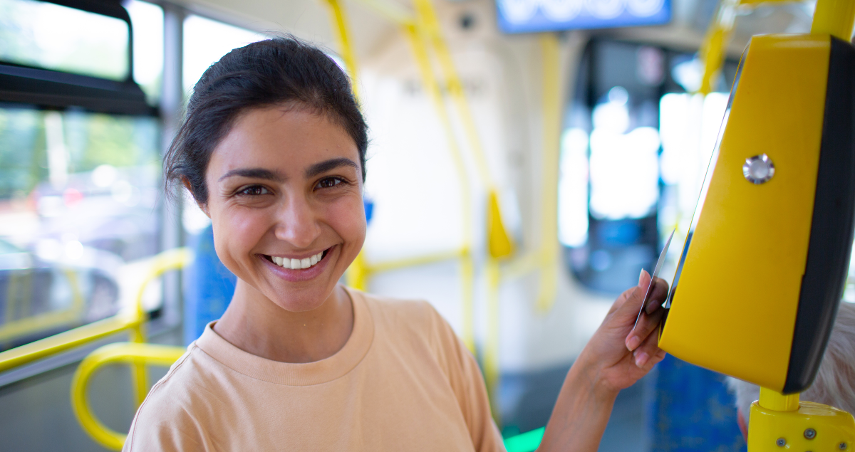 Mulher encostando o cartão em máquina de leitura em ônibus
