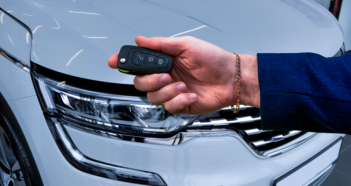 Pessoa segurando chave de carro em frente a veículo