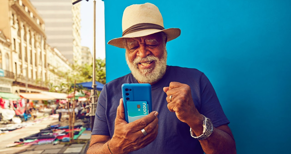 Homem de chapéu e feliz com celular na mão