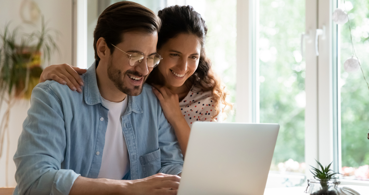 Homem e mulher sorrindo em frente a computador