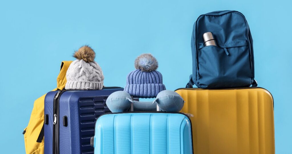 Malas de viagem azuis e amarelas com gorros de frio em cima
