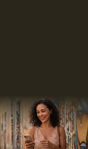 Mulher na rua sorrindo e mexendo em celular