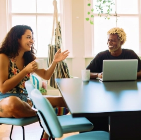 Homem e mulher em volta de uma mesa conversando e sorrindo
