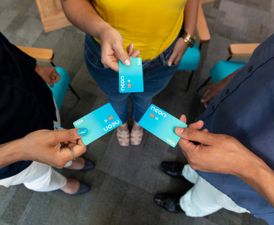 Três pessoas em círculo, cada uma segurando um cartão de crédito Neon na mão