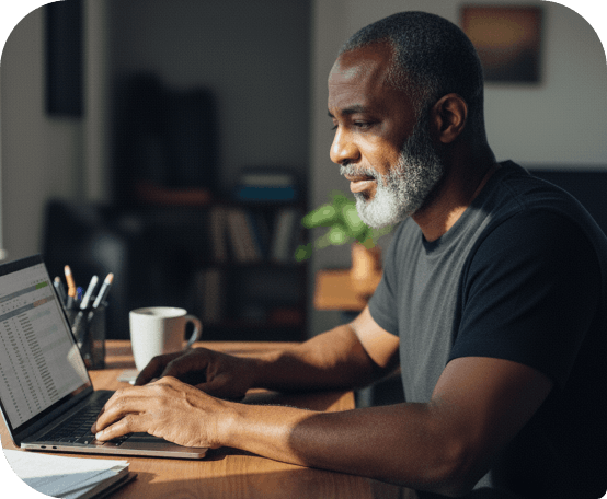 Homem trabalhando em laptop em ambiente doméstico com xícara de café, transmitindo foco e produtividade.