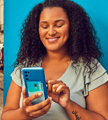 Mulher sorrindo segurando celular na mão em frente a fundo azul escuro