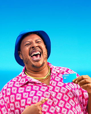 Homem na praia sorrindo segurando cartão de crédito Neon