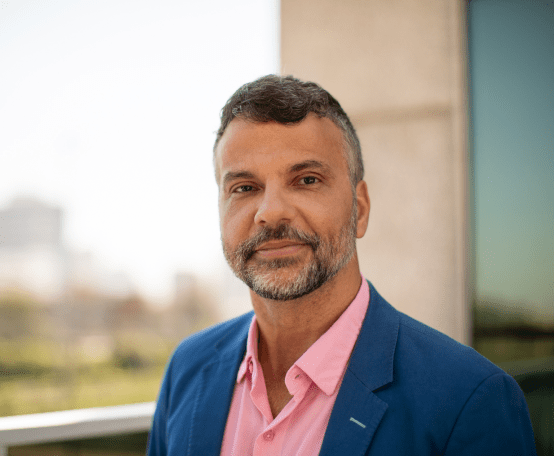 Homem de blazer azul e camisa rosa olhando para frente